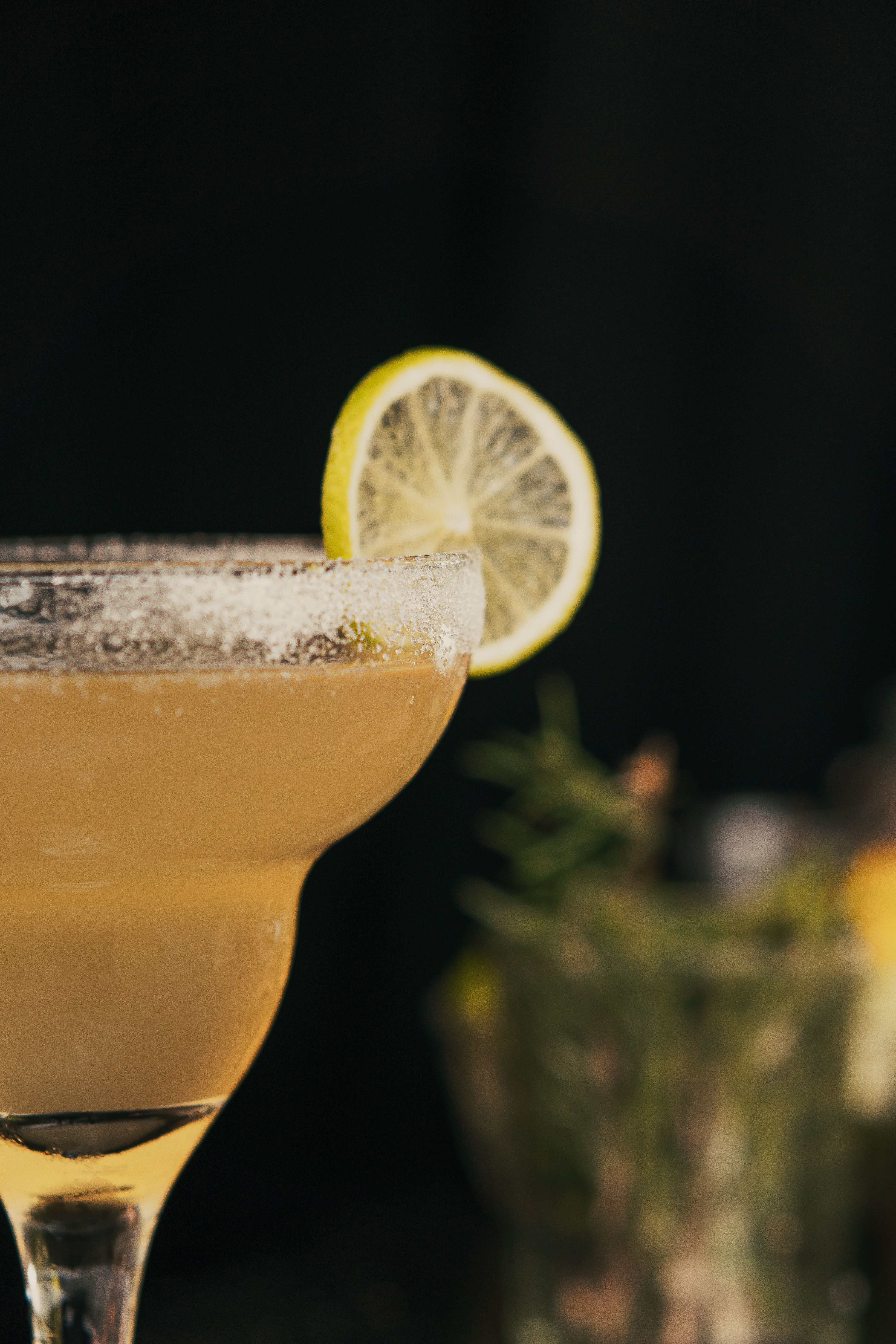 Close-up of a refreshing margarita cocktail garnished with a lemon slice and salt rim.