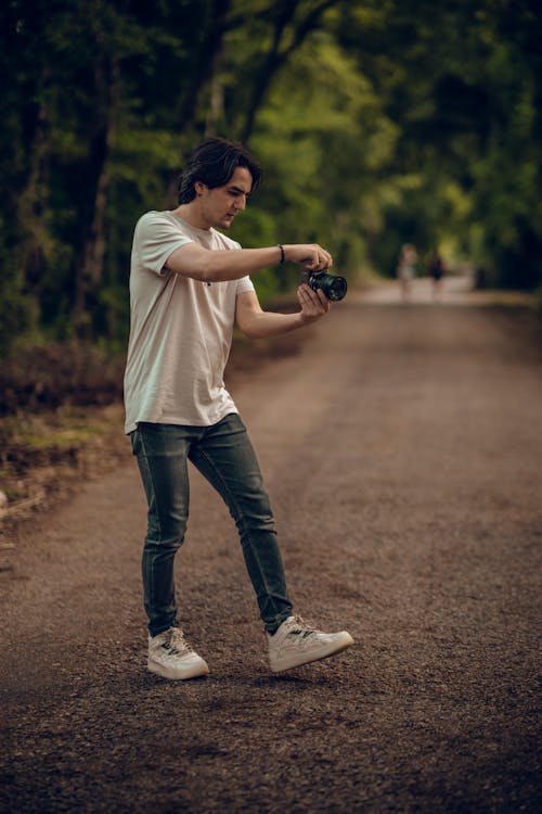 Man Standing on Road in Park Taking Photo