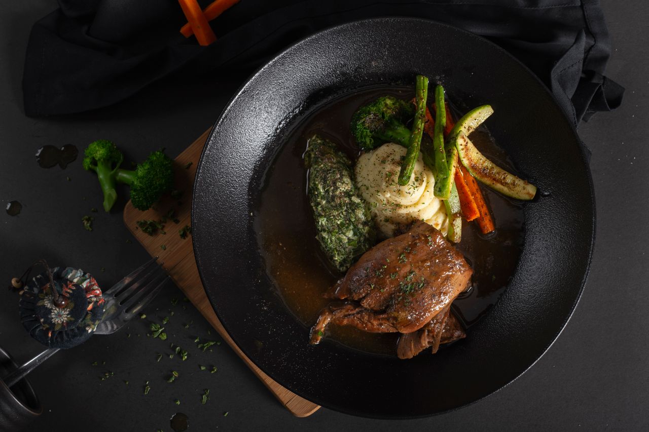 Braised chicken pieces with vegetables and mashed potatoes plated on a rustic table