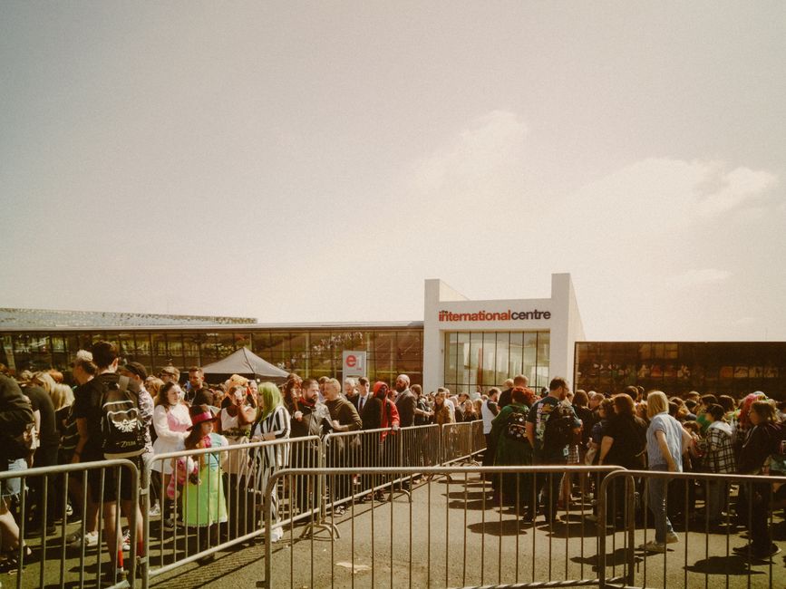 Large crowd gathering outside the International Centre under sunny skies.