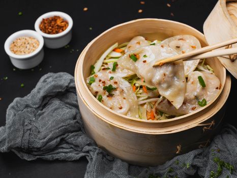 Steamed Asian dumplings with vegetables in a bamboo steamer.