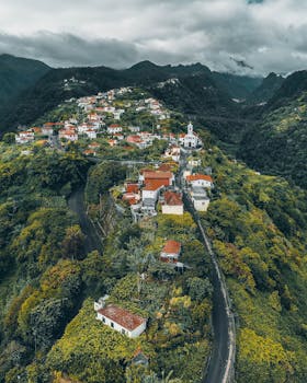 Scenic aerial view of a quaint village in Madeira, Portugal surrounded by lush greenery and mountains.