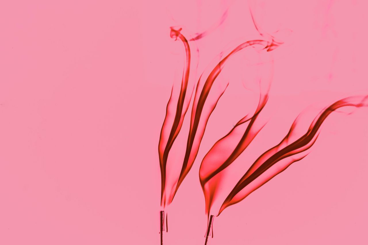 vibrant red smoke swirls elegantly against a soft pink background crea