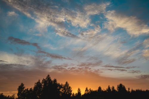 Free Dramatic sunset sky with clouds over a tranquil forest setting. Stock Photo