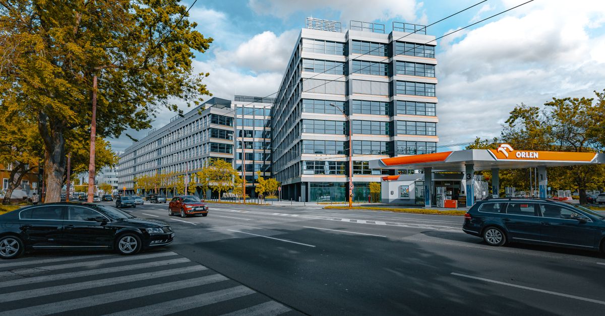 Wide view of a city intersection with modern buildings and an Orlen gas station.