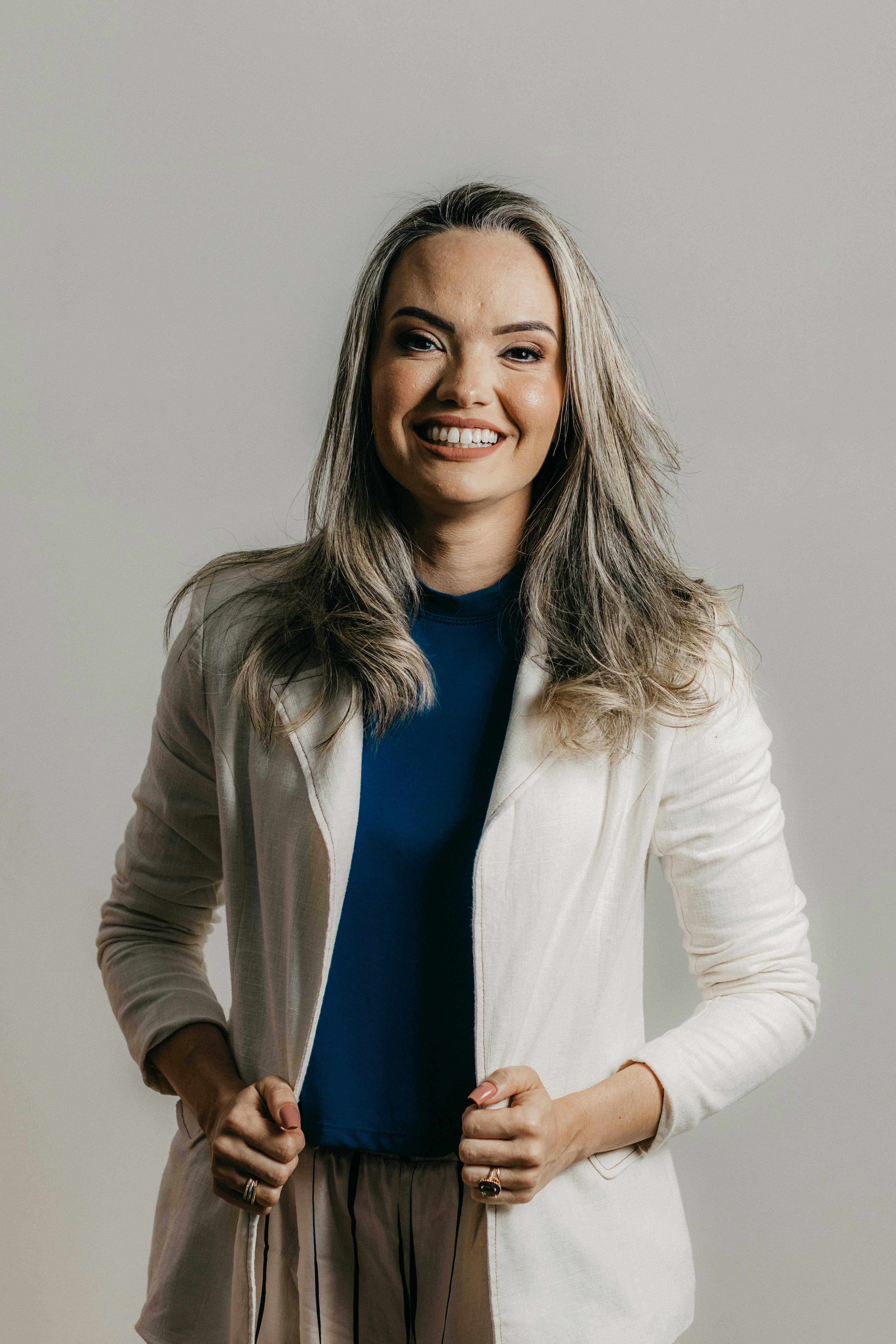 Portrait of a confident businesswoman in a white jacket, smiling gracefully.