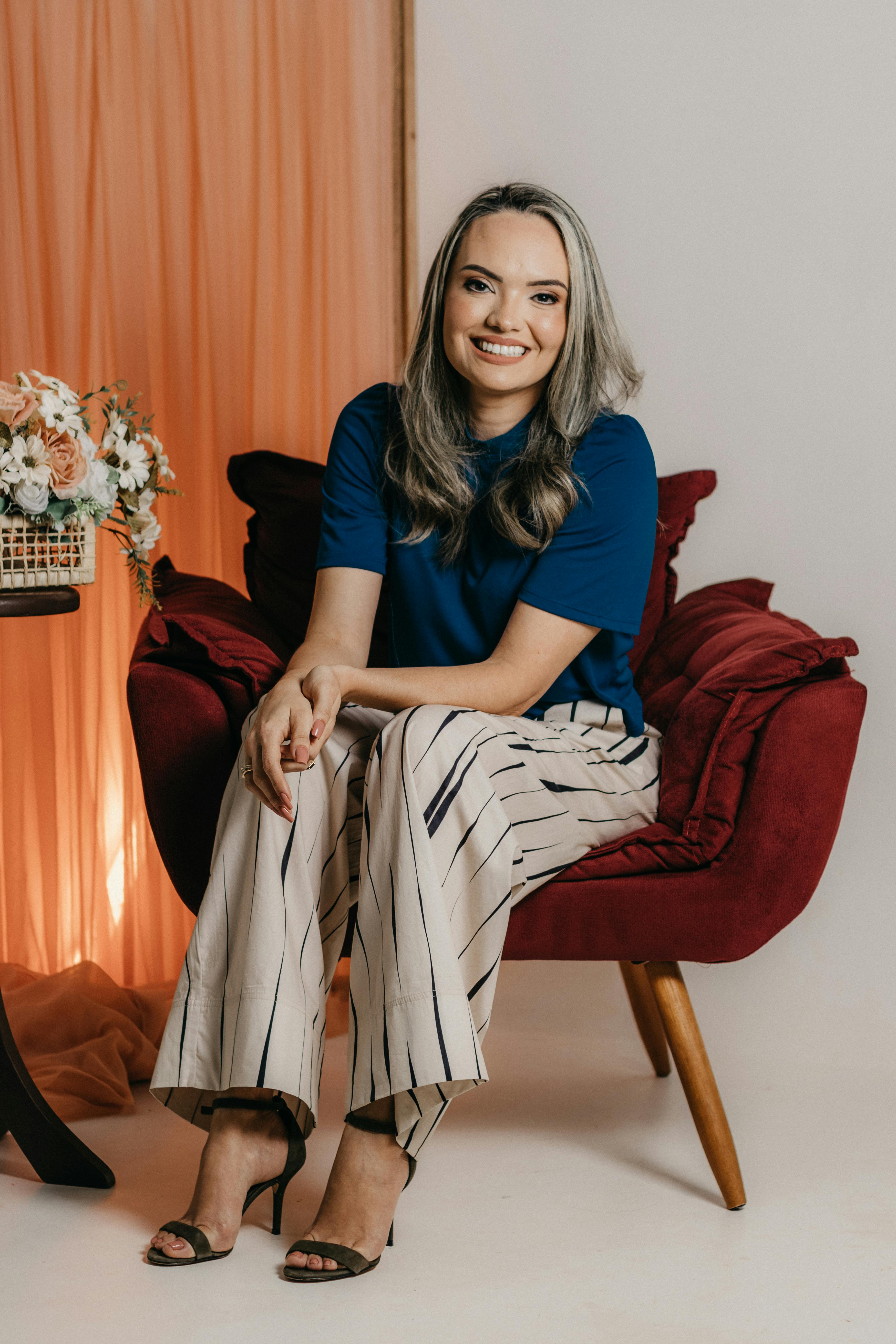 Confident woman in a blue t-shirt and striped pants, smiling in a modern indoor setting.