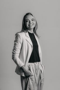 Stylish young businesswoman in grayscale posing confidently in a studio setting.