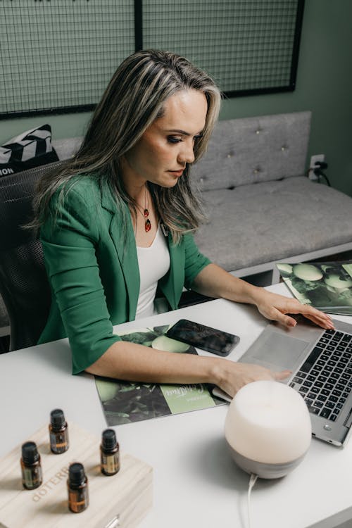 Woman Sitting at a Desk and Typing on a Laptop 