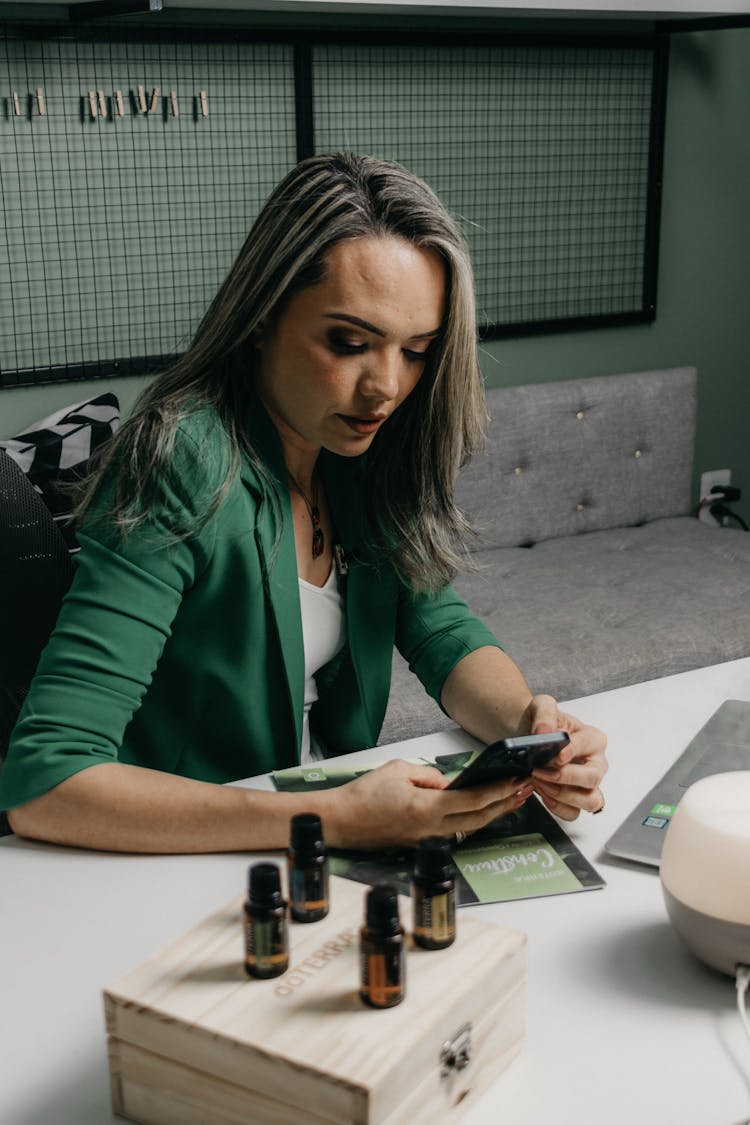 Businesswoman Sitting At Desk With Phone In Hands