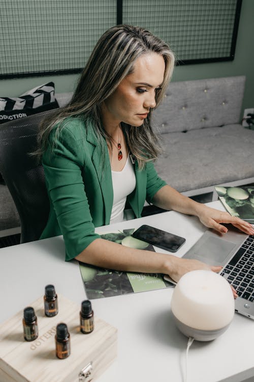 Woman Sitting at a Desk and Typing on a Laptop 