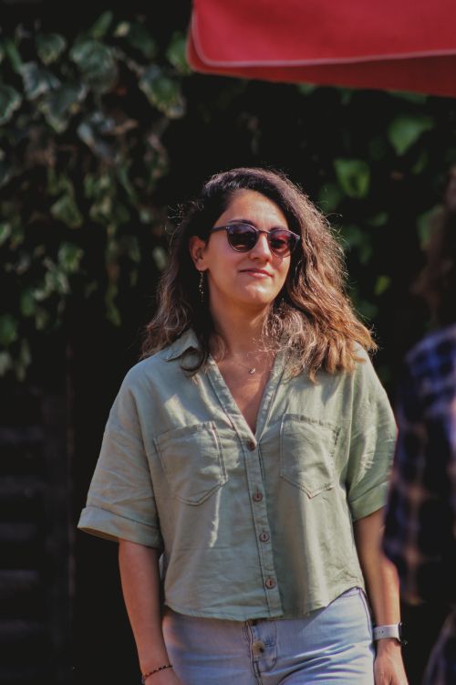 Free Young woman in sunglasses and casual summer outfit, standing outdoors with a confident smile. Stock Photo