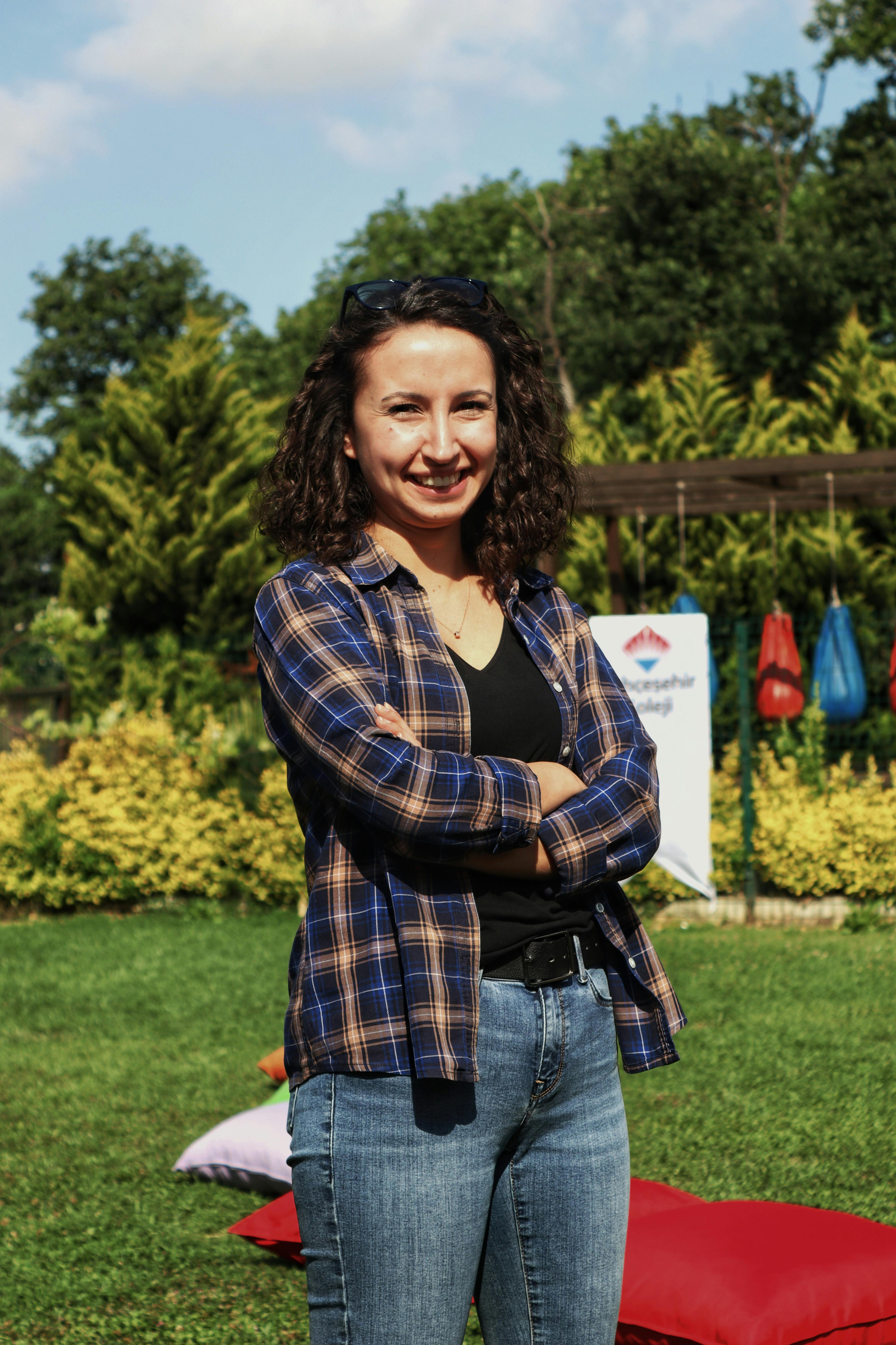 Portrait of a smiling woman outdoors in casual attire, enjoying a sunny day in the park.