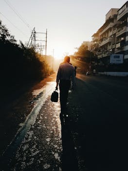 日出时分，印度浦那一条阳光明媚的街道上，一名男子行走的剪影，营造出引人注目的城市景象