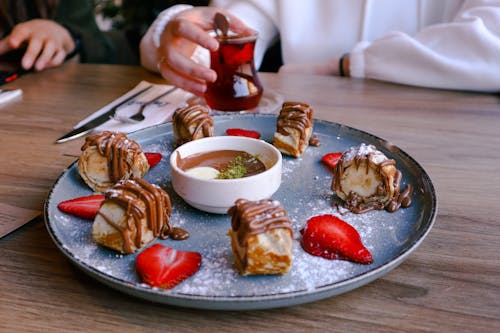 Sweet Cakes on Tray and Hand Holding Turkish Tea behind