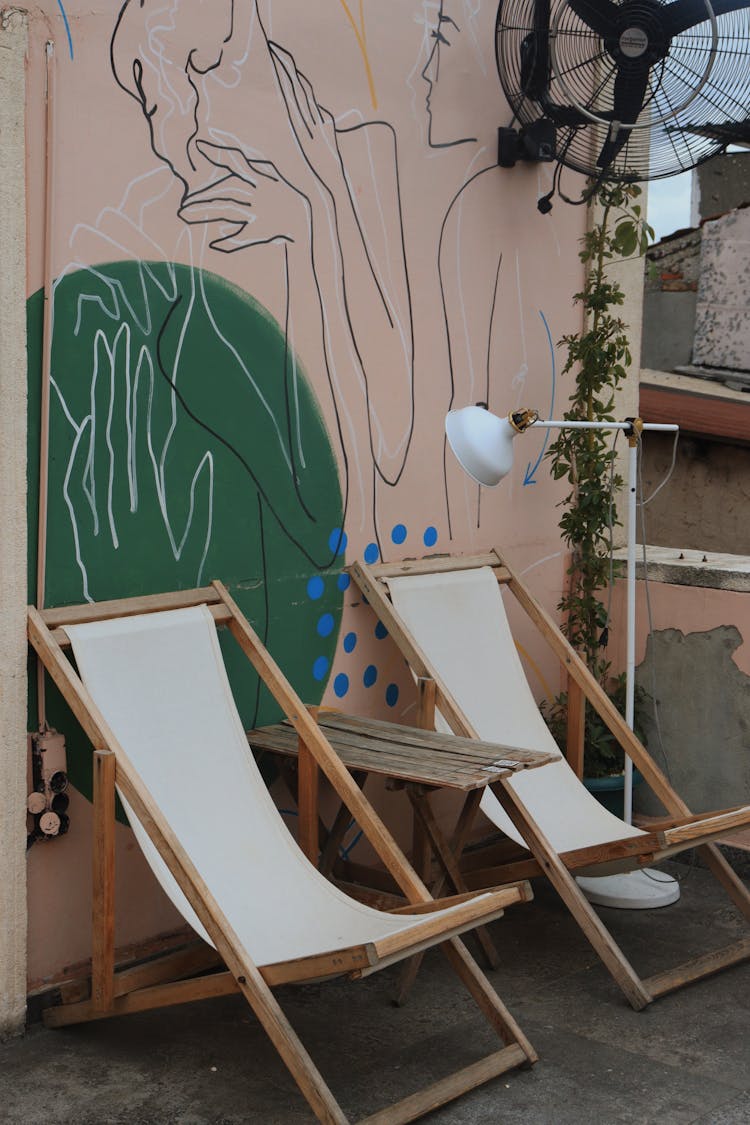 Sunbeds And Table Near Mural On Wall