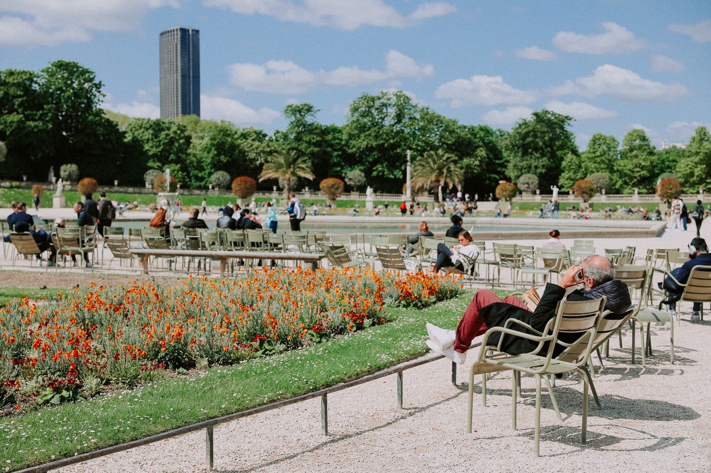 Des promeneurs se reposent au jardin du Luxembourg à Paris, au milieu des fleurs