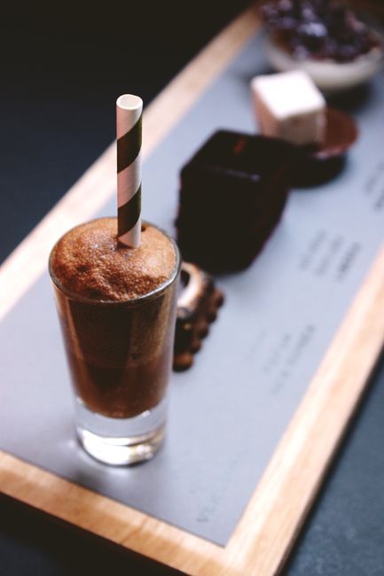 Close-up of a decadent dessert platter featuring a chocolate drink with straw.