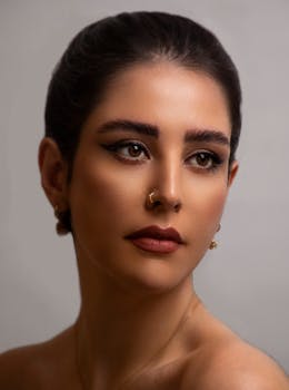 A beautifully lit portrait of a woman with striking eye makeup and nose ring.