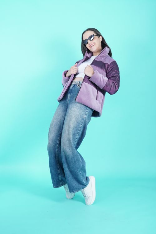 Free Trendy woman in jeans and winter jacket posing against a blue background. Stock Photo