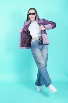Stylish young woman in jeans and purple jacket posing confidently in a vibrant studio setting.
