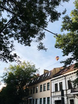 宁静的城镇里，绿树成荫的街道上空飘着色彩缤纷的热气球