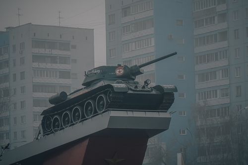 Free A military tank monument on a platform with residential buildings in the background. Stock Photo