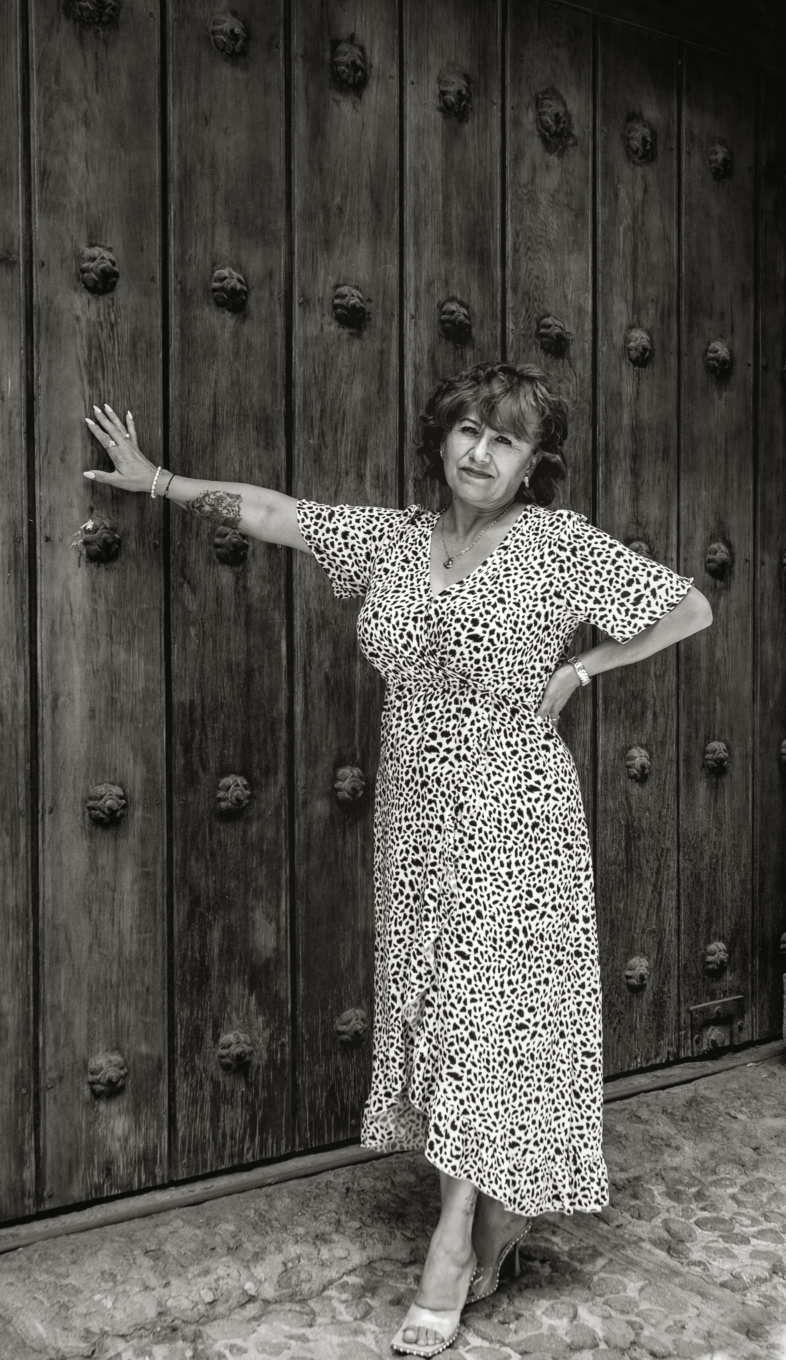 Stylish woman poses against a rustic wooden door in Puebla, Mexico.