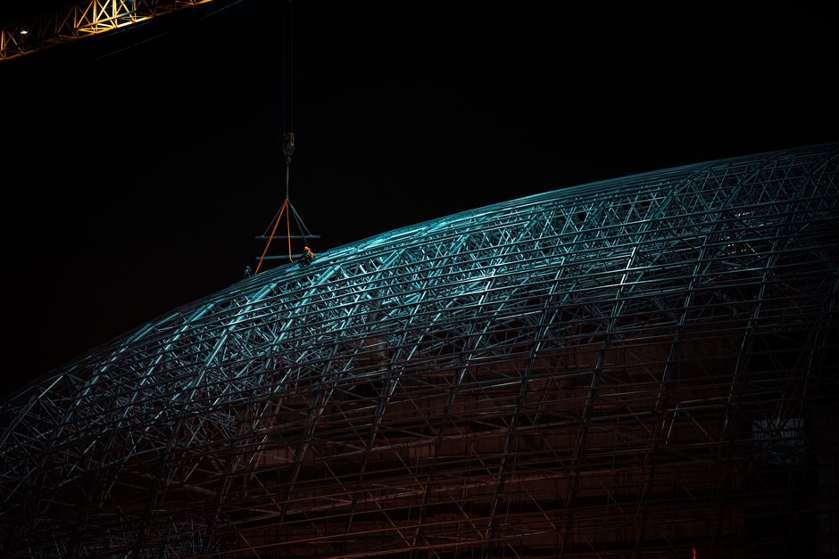 Captivating night view of dome construction with cranes in Kuwait City.