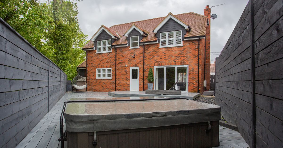 A picturesque backyard view of a modern brick house with a jacuzzi.