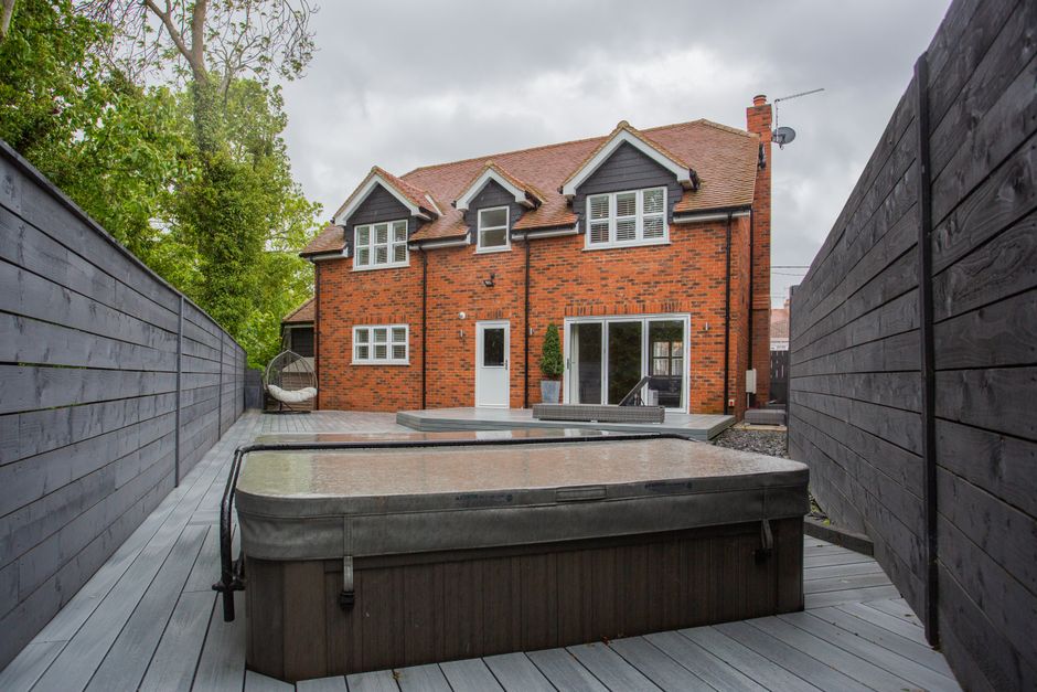 A picturesque backyard view of a modern brick house with a jacuzzi.