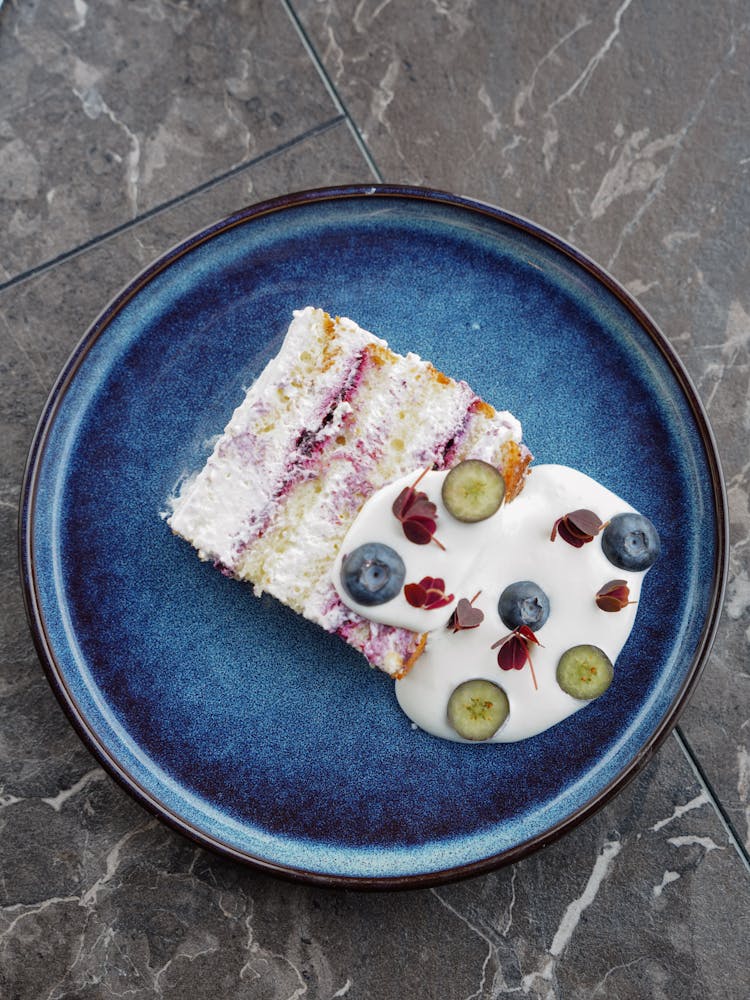 Slice Of Cake With Yogurt On Blue Plate