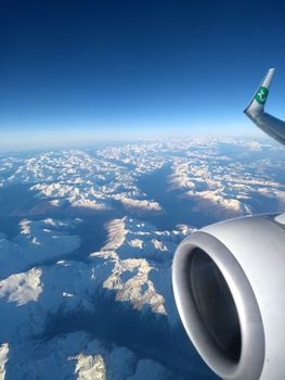 Stunning aerial view of the snow-covered Alps seen from a commercial airplane, enhancing travel vibes.