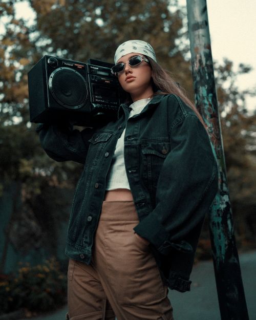 Free Stylish woman wearing sunglasses holds a retro boombox. Embracing youth culture. Stock Photo