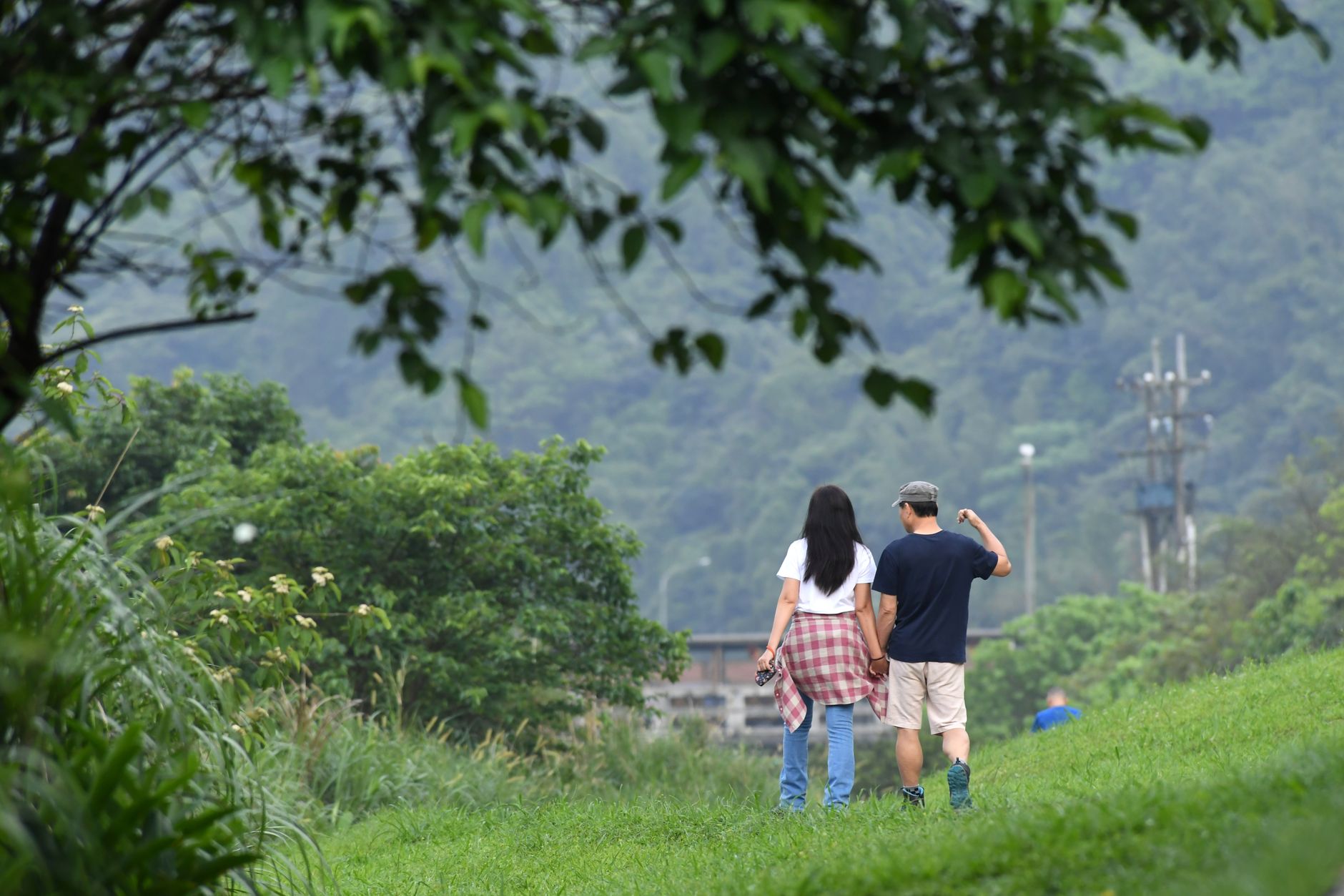 新北熱門景點避開人潮時間與替代選擇:實用日程與路線規劃 A couple walks hand in hand through a lush green landscape in Nuannuan District, Taiwan.