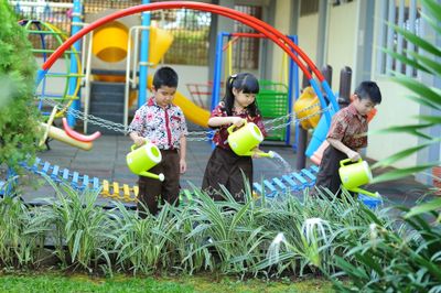 Young kids learning gardening skills by watering plants