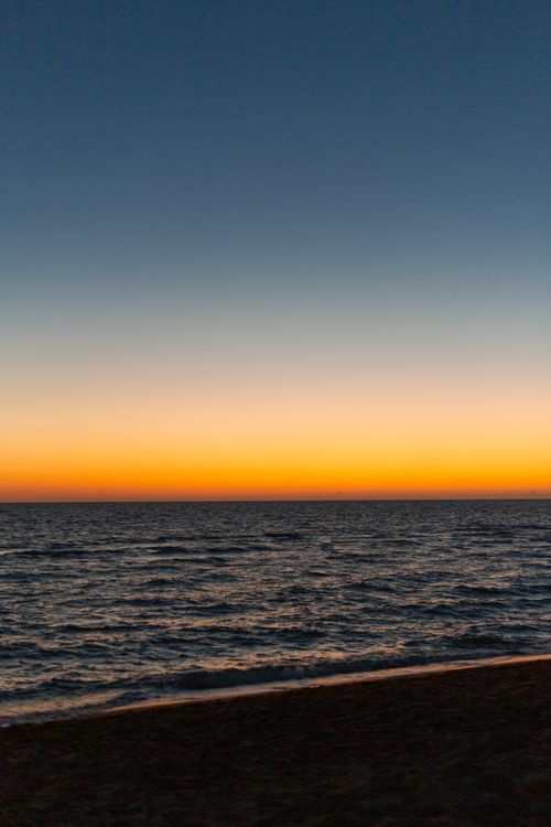Free A serene seascape featuring a tranquil sunset over the ocean with a vibrant horizon. Stock Photo