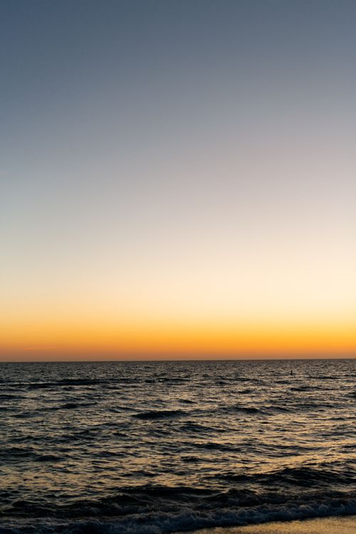 Free Peaceful ocean view with a stunning sunset creating vivid hues on the horizon. Stock Photo