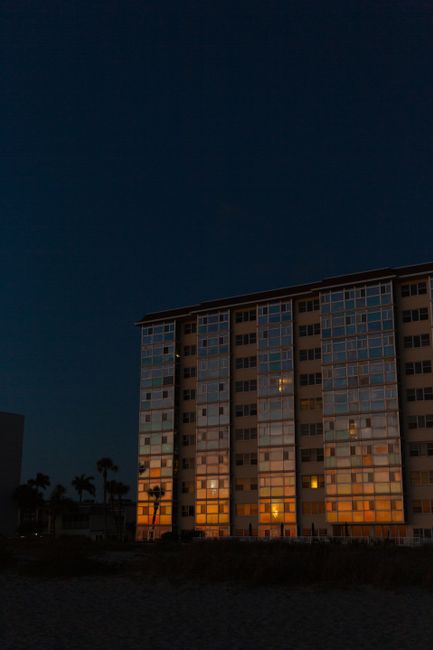 Evening shot of a residential building with window reflections at sunset.