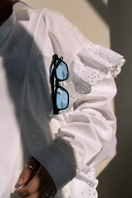 Close-up of a stylish outfit with sunglasses in natural light.