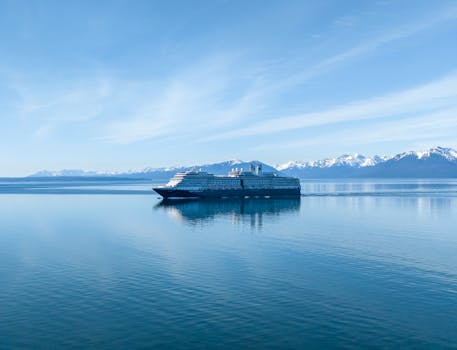 A cruise ship sails through serene waters with snowcapped mountains in the background in Hoonah, Alaska.