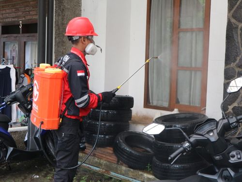 Pest control technician in safety helmet spraying