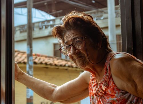 Free A senior woman with glasses gazing out of a window in Cali, Colombia. Stock Photo