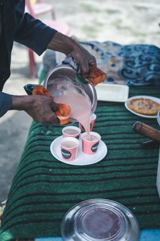Man pours traditional Kashmiri beverage into cups at an outdoor stall in Srinagar.