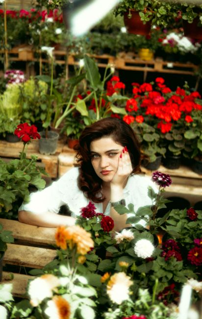 Portrait of a woman surrounded by vibrant flowers in a garden setting in Azerbaycan.