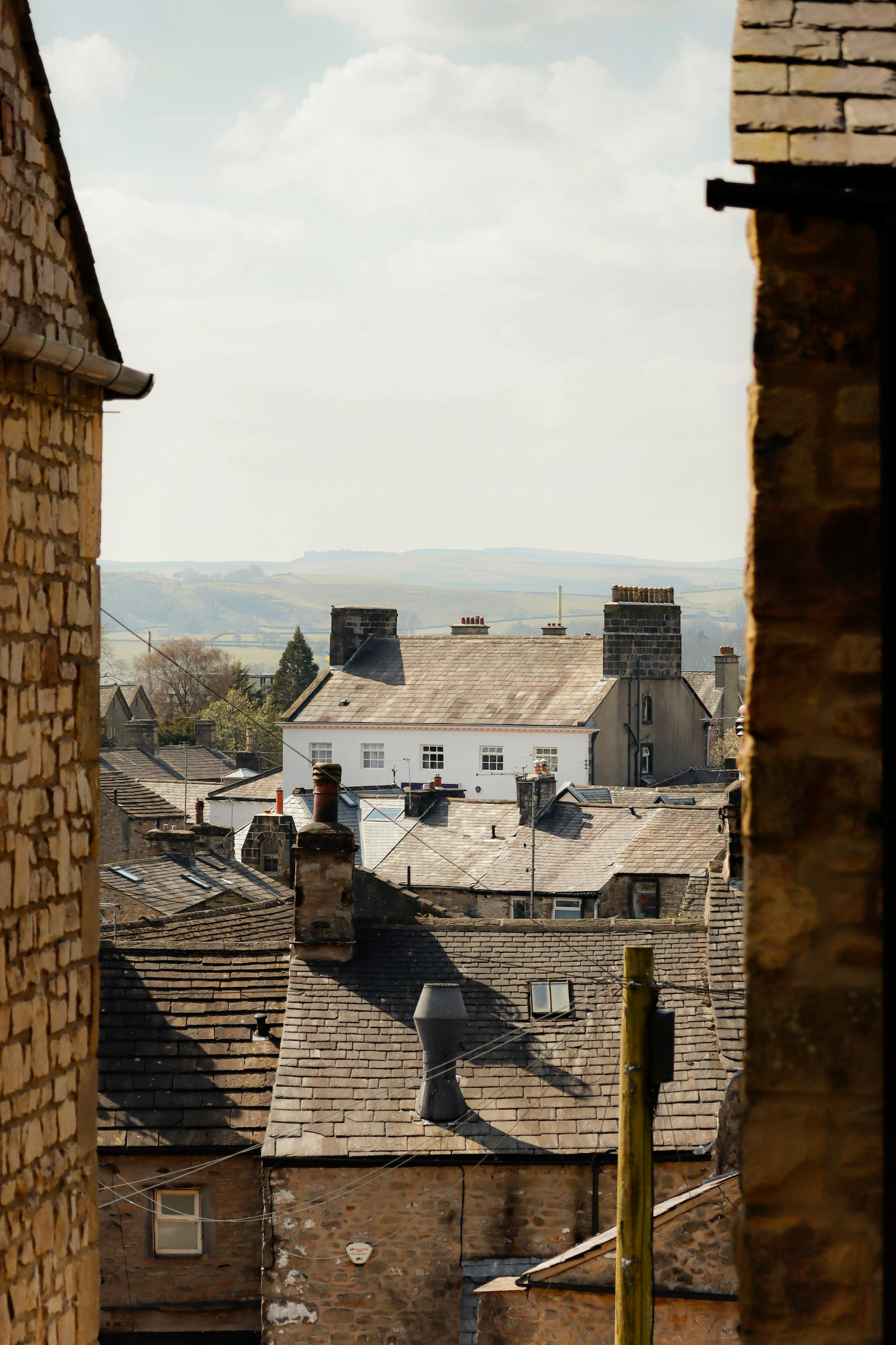 View of rustic village rooftops with stone architecture and distant hills.
