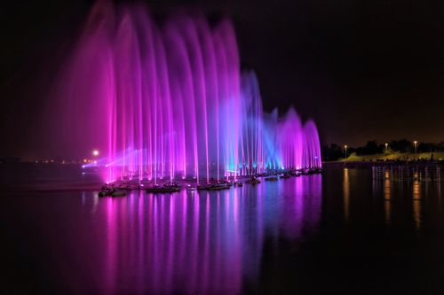 Free Colorful illuminated water fountains reflecting on the river at night. Captivating display of vibrant lights and reflections. Stock Photo