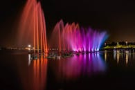 夜晚，城市河流上倒映着色彩缤纷的灯光，与充满活力的喷泉交相辉映