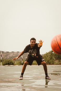 A teenager playing basketball on an outdoor court during the day, showcasing athletic energy.