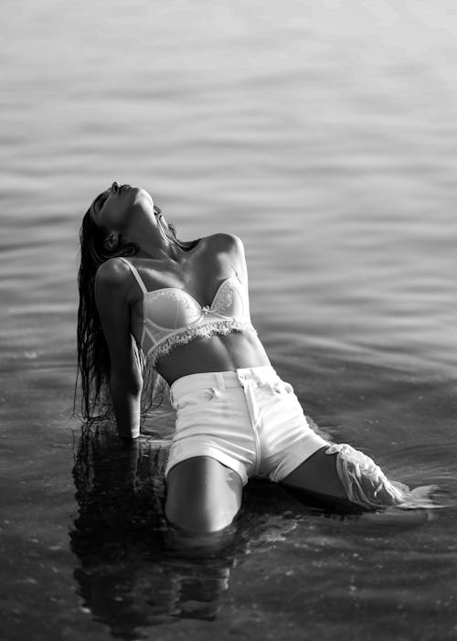 Grayscale Shot of a Woman Kneeling and Leaning Backwards in the Water